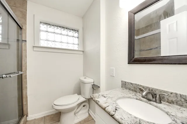 a bathroom with a granite countertop sink toilet and a mirror