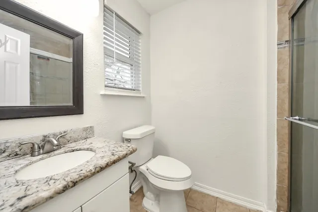 a bathroom with a granite countertop sink toilet and mirror