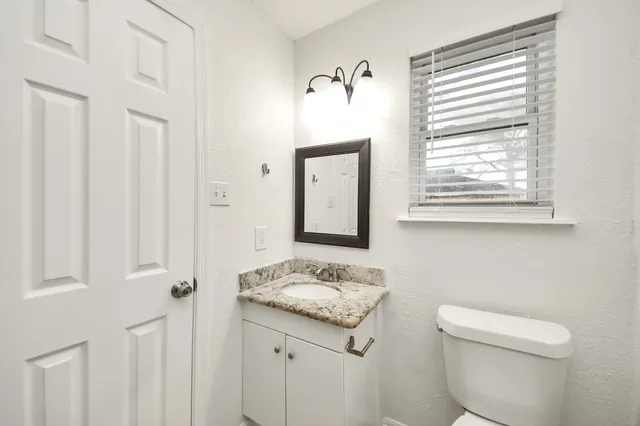 a bathroom with a sink a toilet and a window