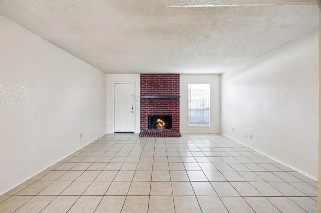 a view of an empty room with a fireplace and a window