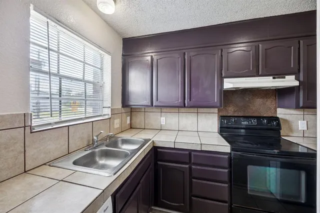 a kitchen with granite countertop a sink stove and cabinets