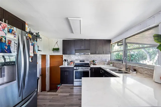 a kitchen with stainless steel appliances granite countertop a refrigerator a sink a stove and a refrigerator