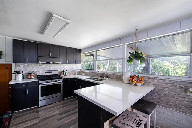 a kitchen with stainless steel appliances granite countertop a sink a stove and a wooden floors