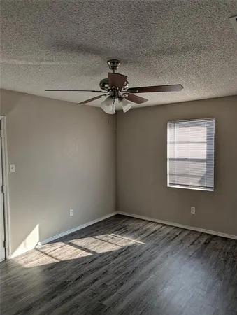 a view of a room with wooden floor a ceiling fan and windows