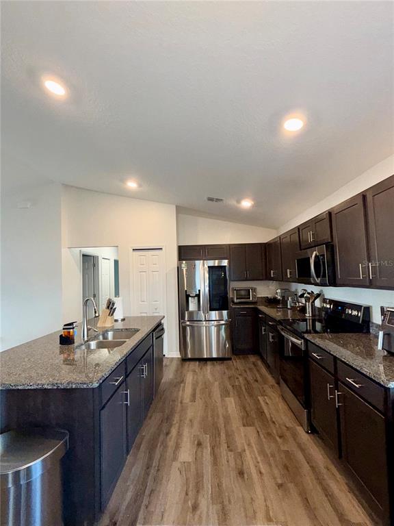 4448 Reding Way Lakeland, FL 33813 - Photo 8 of 26 a kitchen with stainless steel appliances granite countertop a stove top oven a sink dishwasher and wooden cabinets with wooden floor