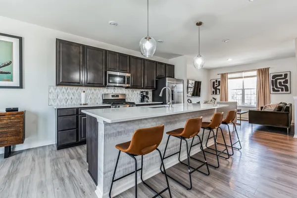 a kitchen with stainless steel appliances granite countertop a refrigerator a stove a sink dishwasher a dining table and chairs with wooden floor