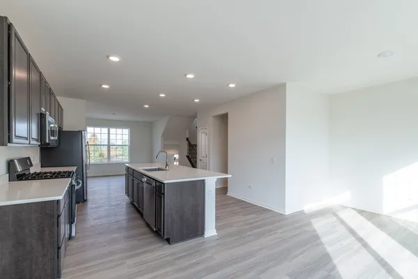 a living room with stainless steel appliances kitchen island granite countertop furniture and a wooden floor