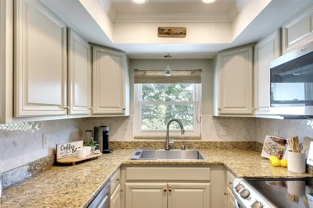 a kitchen with stainless steel appliances granite countertop a sink a stove and cabinets