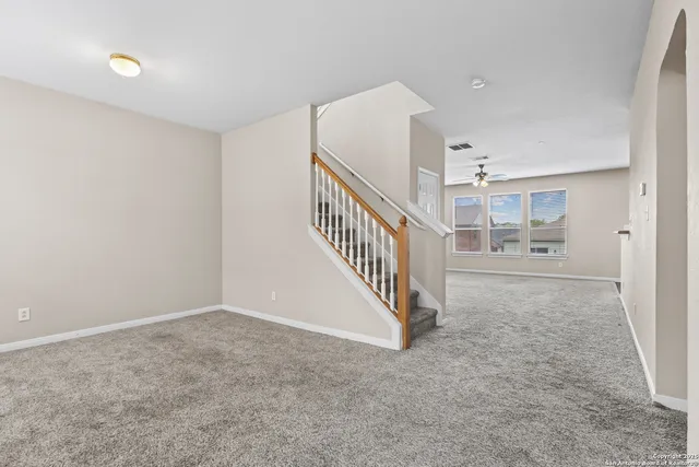 a view of an empty room with chandelier fan and fire place