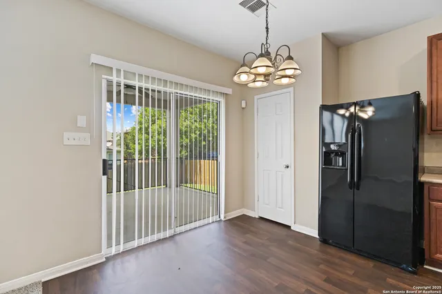 a kitchen with stainless steel appliances granite countertop a refrigerator a sink dishwasher a oven and a dining table with wooden floor