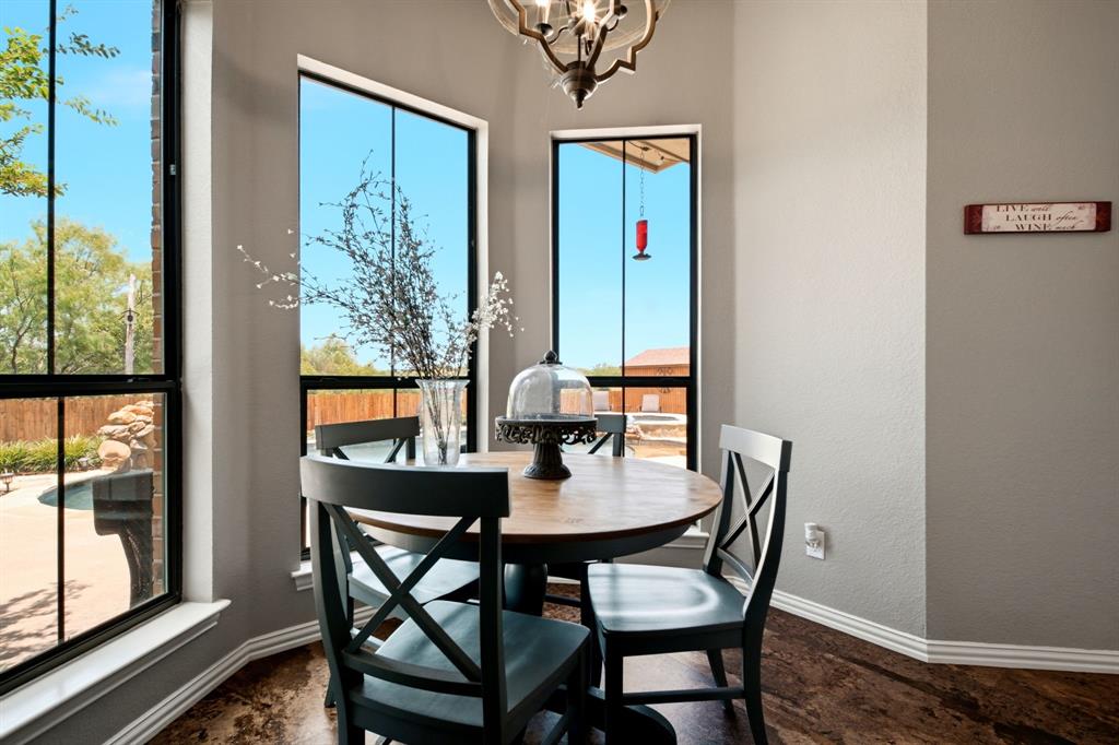 600 Aspen Street Pilot Point, TX 76258 - Photo 16 of 39 Breakfast nook with three large windows, a decorative chandelier, and wood-finish flooring