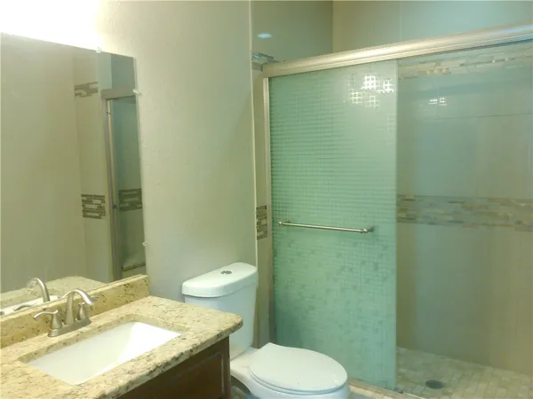 a bathroom with a granite countertop sink toilet and shower