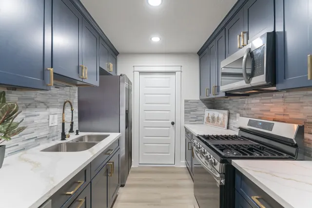 a kitchen that has a sink wooden cabinets and stainless steel appliances