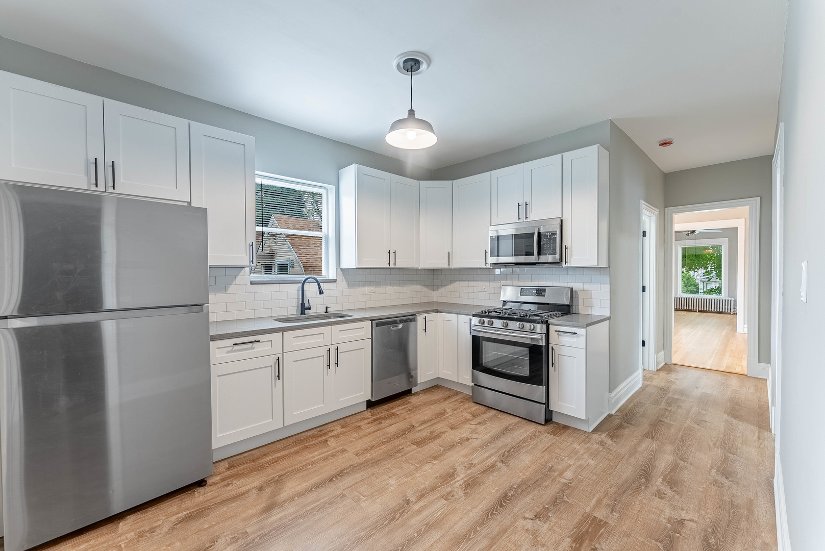 4730 West Warwick Avenue, Unit 2 Chicago, IL 60641 - Photo 16 of 26 a kitchen with granite countertop white cabinets a sink stainless steel appliances and a window