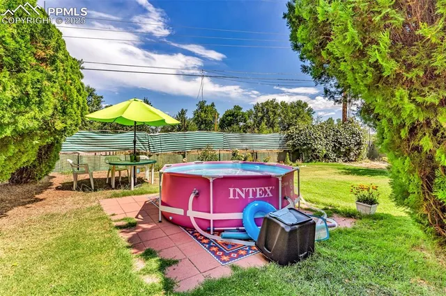 a view of a yard with table and chairs under an umbrella