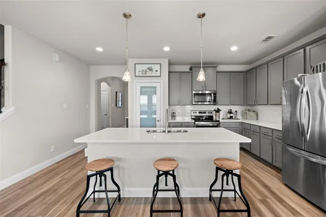 a kitchen with stainless steel appliances granite countertop a dining table chairs refrigerator and cabinets