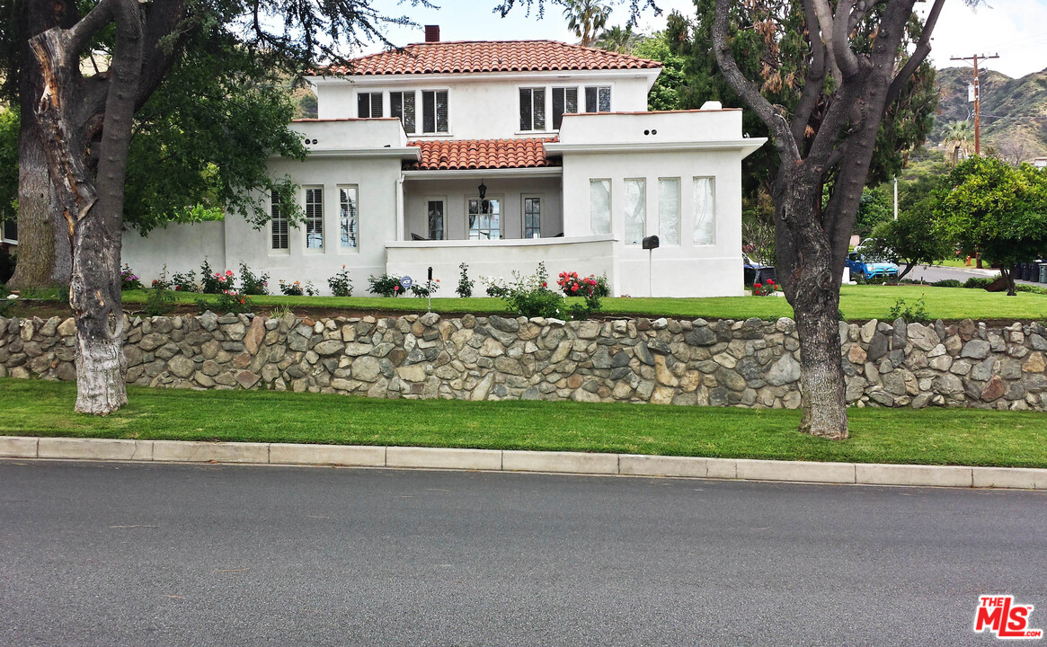 a white house with a small yard and large trees