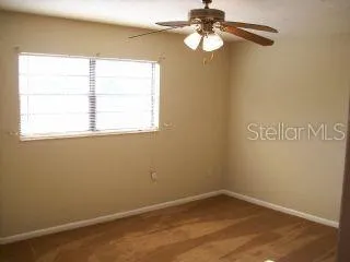 an empty room with a window and a fan