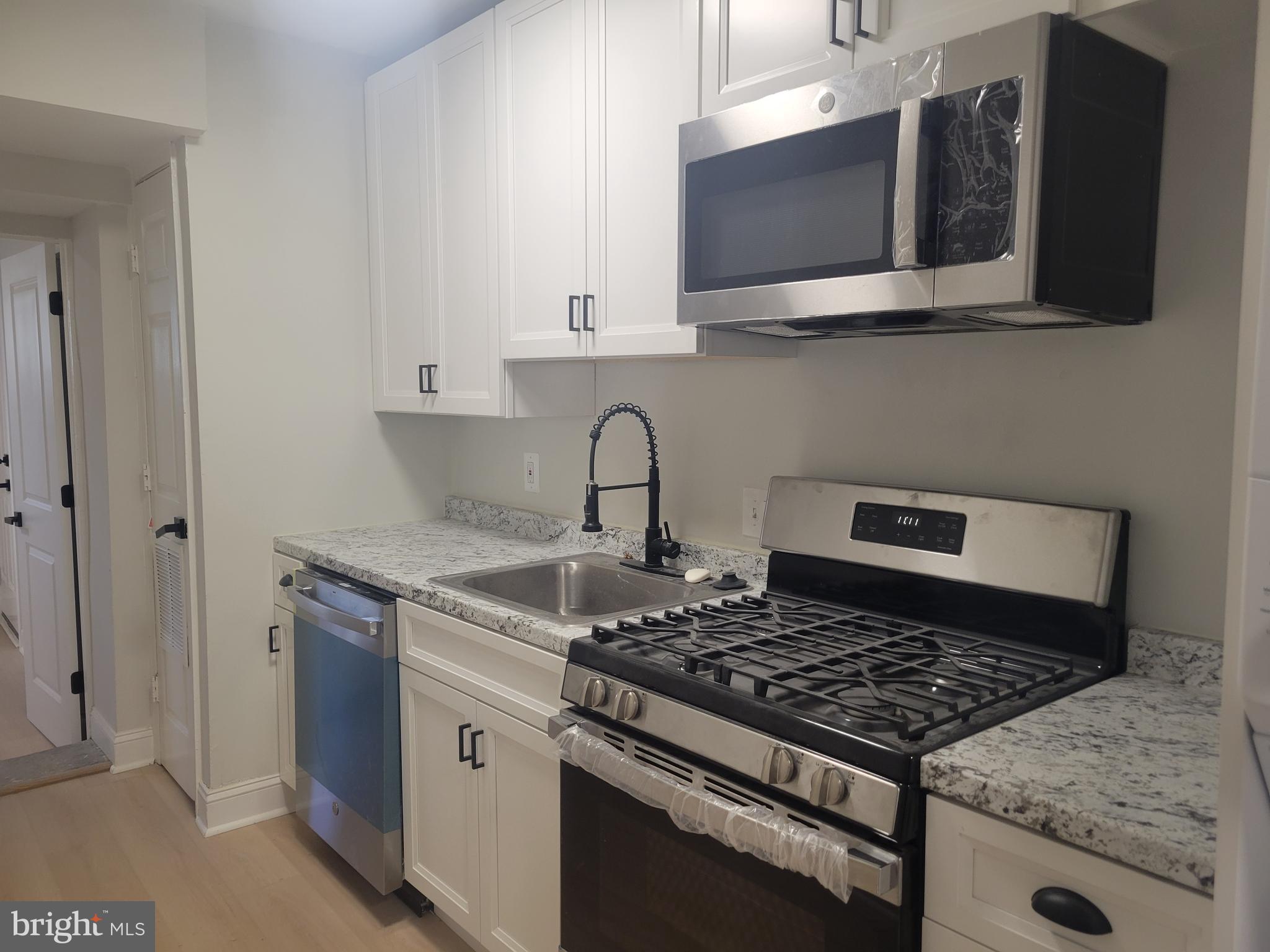 1250 Queen Street Northeast, Unit 1 Washington, DC 20002 - Photo 11 of 13 a kitchen with stainless steel appliances granite countertop a stove and a microwave