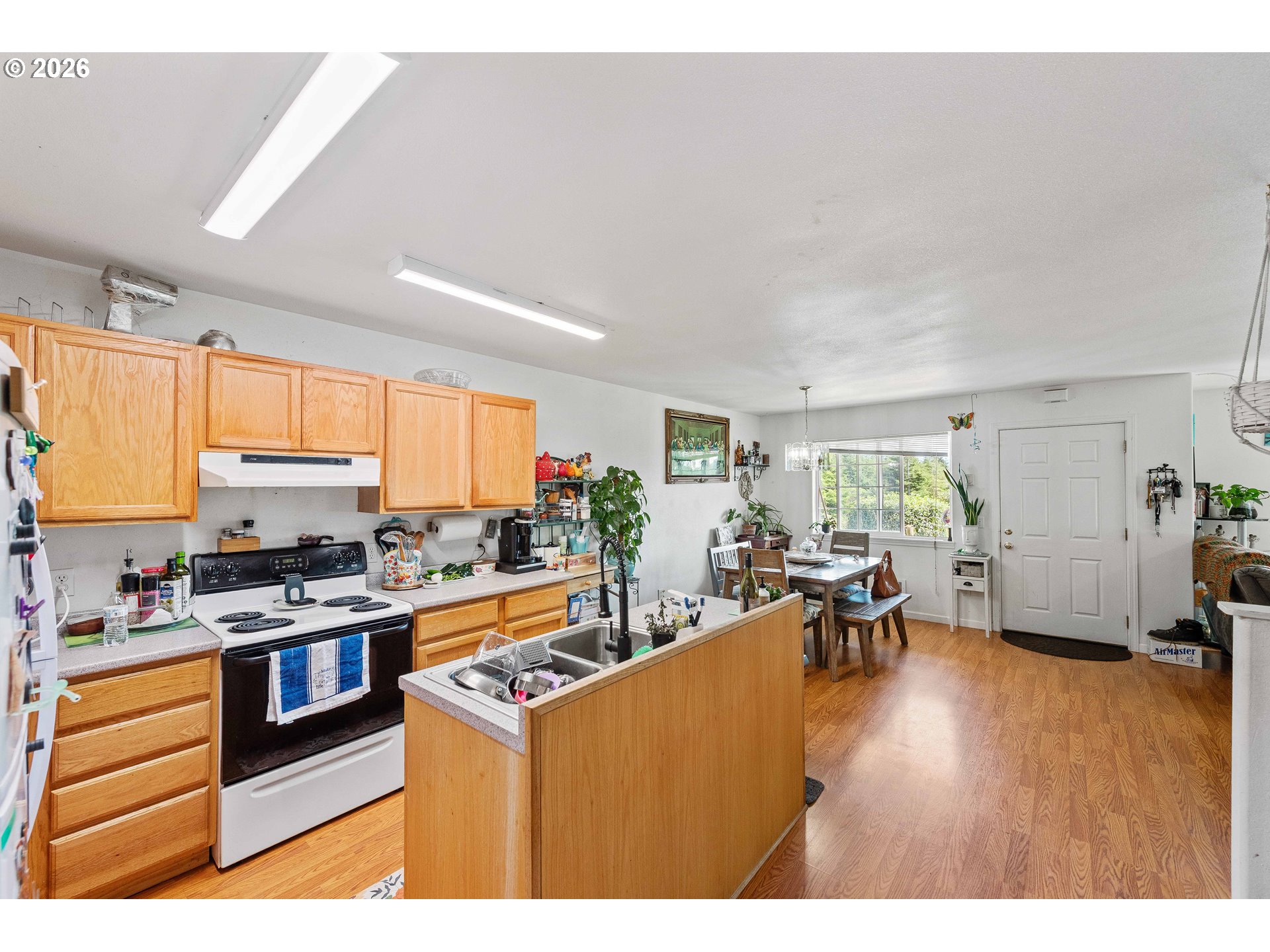 1123 South Morrison Street Coos Bay, OR 97420 - Photo 6 of 47 a kitchen with stainless steel appliances a stove a sink a refrigerator a dining table and chairs with wooden floor