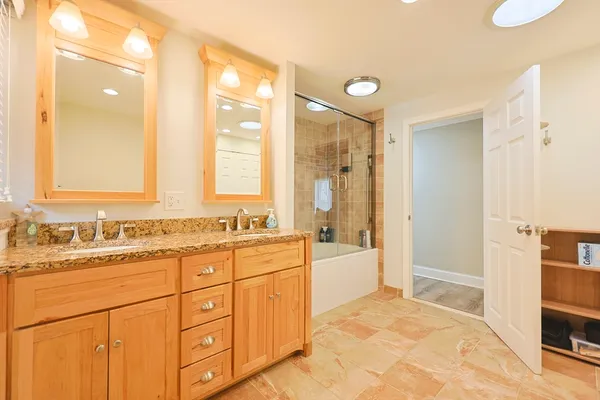 a bathroom with a sink vanity granite tub shower and a mirror