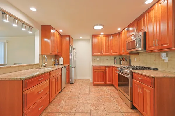 a large kitchen with stainless steel appliances granite countertop a stove a sink dishwasher and a refrigerator