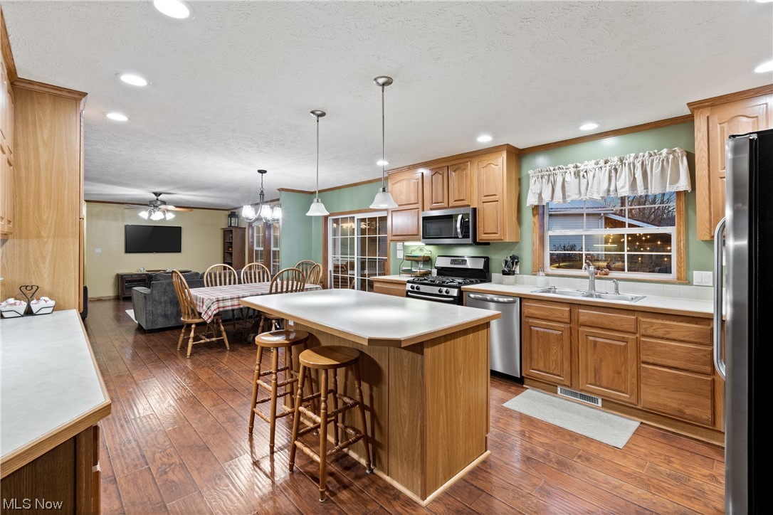 2240 Prysi Road Northwest Dover, OH 44622 - Photo 14 of 35 Kitchen with a kitchen bar, sink, a kitchen island, dark hardwood / wood-style floors, and appliances with stainless steel finishes