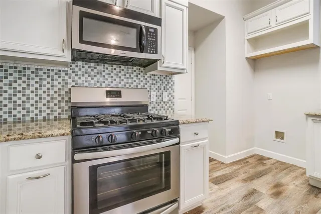 a kitchen with stainless steel appliances granite countertop a stove and white cabinets