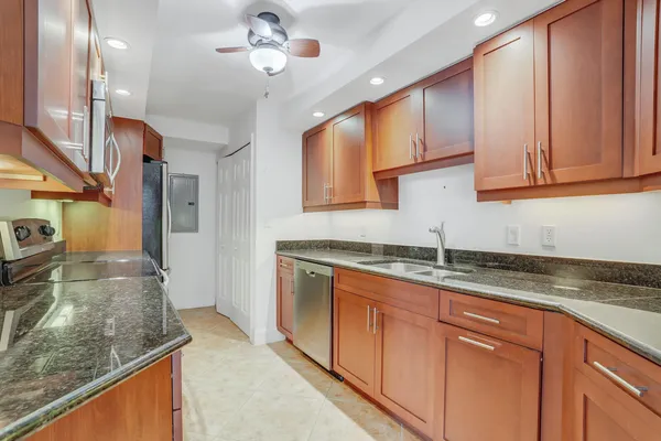 a kitchen with granite countertop a sink a counter top space cabinets and stainless steel appliances