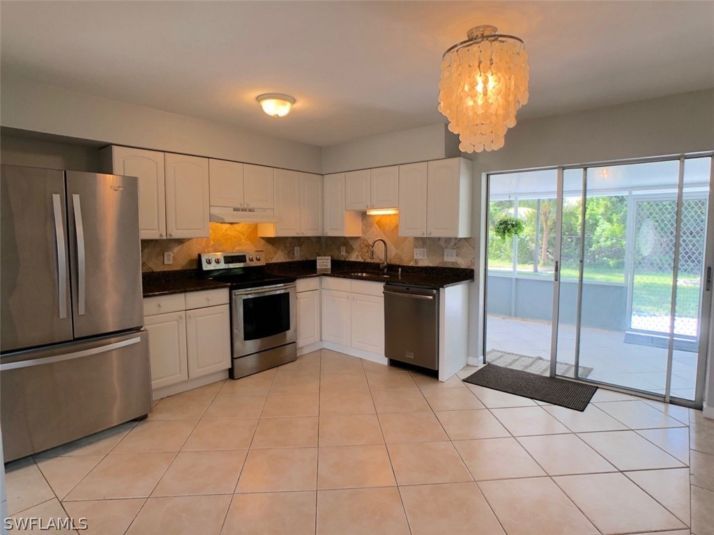 8038 Matanzas Road Fort Myers, FL 33967 - Photo 6 of 27 a kitchen with granite countertop a refrigerator and white cabinets