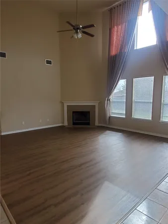 an empty room with wooden floor fireplace and windows