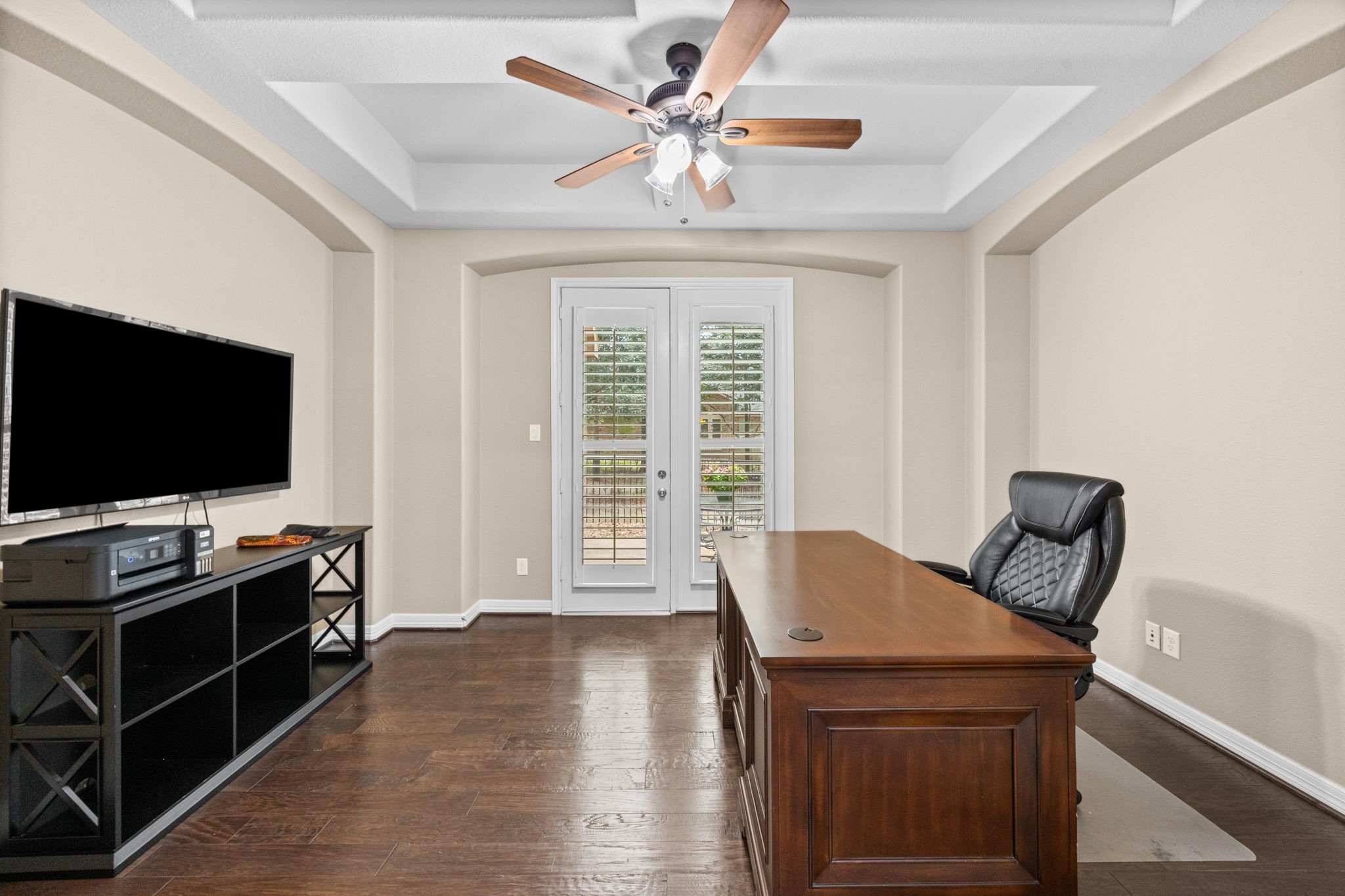 27642 Linden Ridge Lane Fulshear, TX 77441 - Photo 12 of 42 The home office is perfect for executives or remote work, featuring gorgeous, coffered ceilings, rich wood flooring, and elegant double French doors with Plantations Shutters that open to your own private outdoor patio, creating a refined and inspiring workspace with seamless indoor-outdoor access.