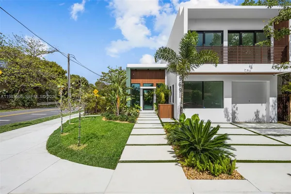 a front view of a house with a garden and plants