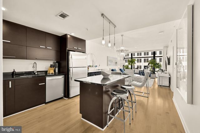 a kitchen with stainless steel appliances kitchen island granite countertop a table chairs and a refrigerator