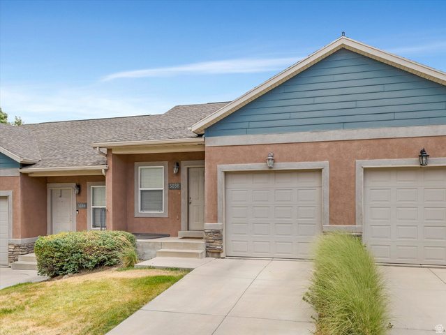 5038 West Red Shale Road Herriman, UT 84096 - Photo 3 of 16 Townhome exterior featuring stucco siding, two integrated garages with panel doors, stone accents, and a blue horizontal siding gable