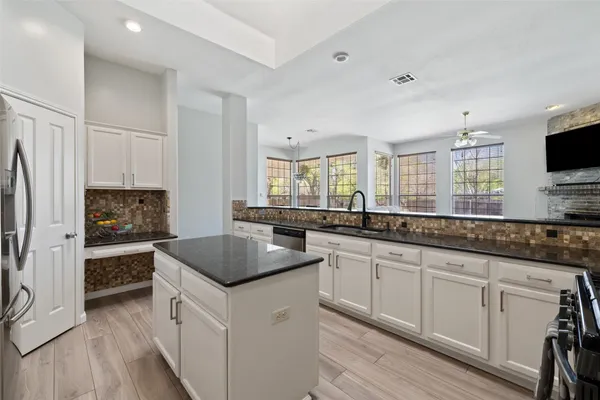 a kitchen with granite countertop a sink stove and refrigerator