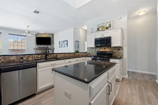 a kitchen with granite countertop a sink and a stove top oven with wooden floor