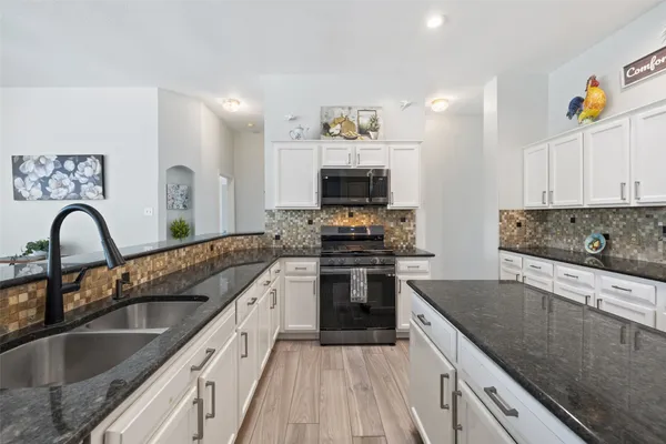 a kitchen with kitchen island granite countertop a sink and appliances