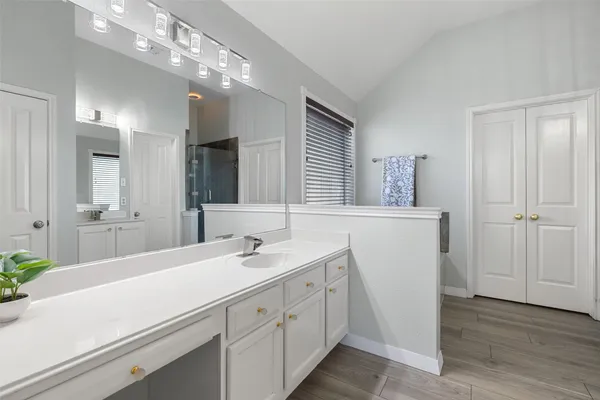 a spacious bathroom with double vanity a mirror and a shower