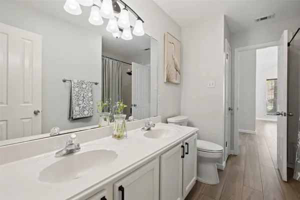 a bathroom with a double vanity sink mirror and toilet