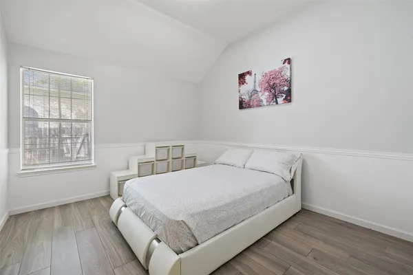 a view of a bedroom with wooden floor and window