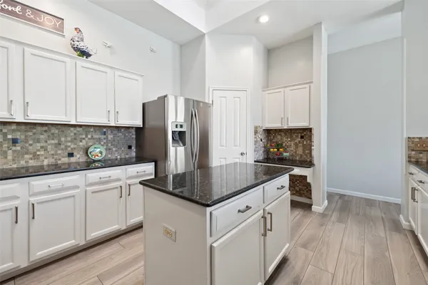a kitchen with stainless steel appliances granite countertop a refrigerator a sink and white cabinets