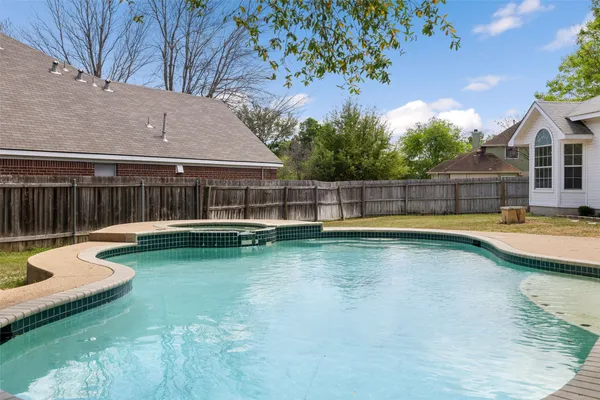 a view of swimming pool with seating area and trees in the background