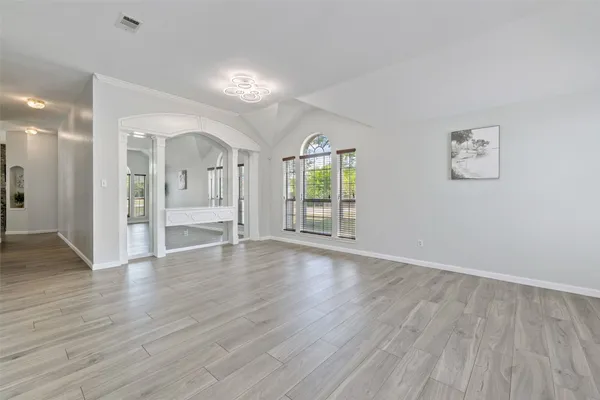 an empty room with wooden floor and windows