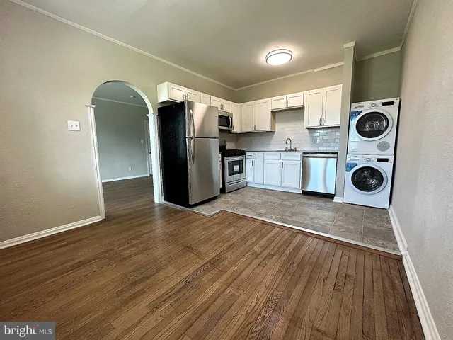 a view of kitchen with stainless steel appliances wooden floor and cabinets