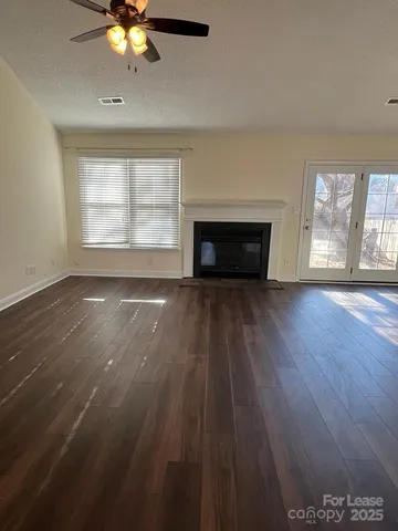 an empty room with wooden floor fireplace and windows