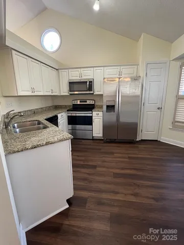 a kitchen with stainless steel appliances granite countertop a refrigerator a stove and a sink