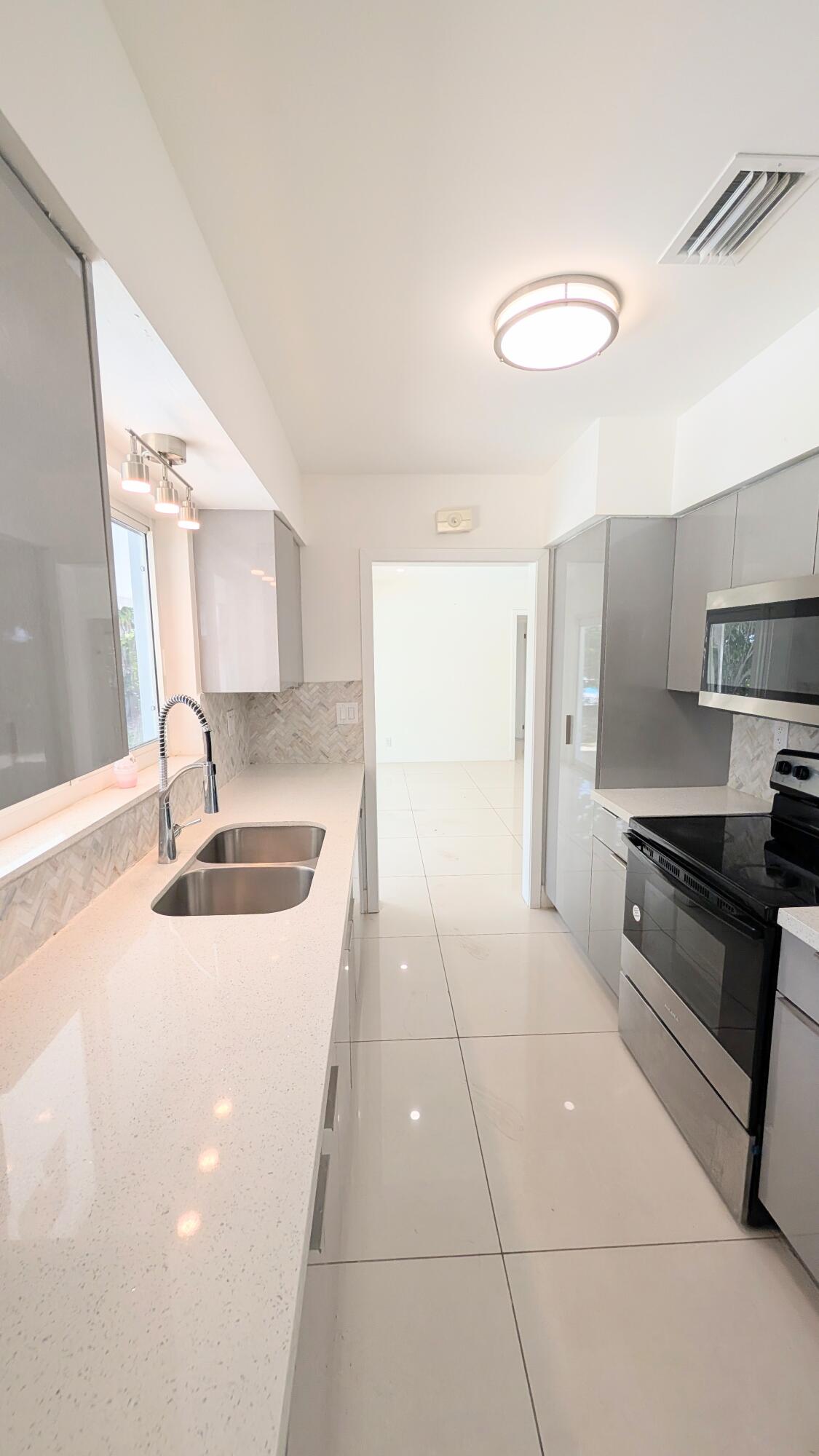 3840 Northeast 22nd Terrace Lighthouse Point, FL 33064 - Photo 16 of 18 a kitchen with stainless steel appliances a sink stove and cabinets