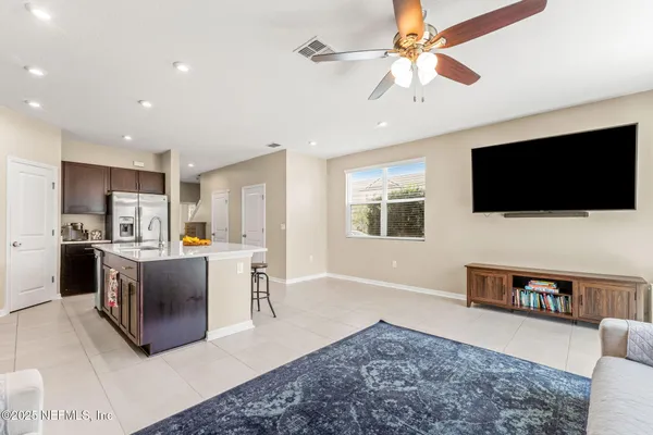 a living room with stainless steel appliances kitchen island granite countertop a couch and a flat screen tv