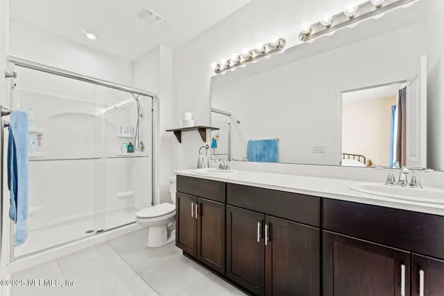 a bathroom with a double vanity sink toilet mirror and shower